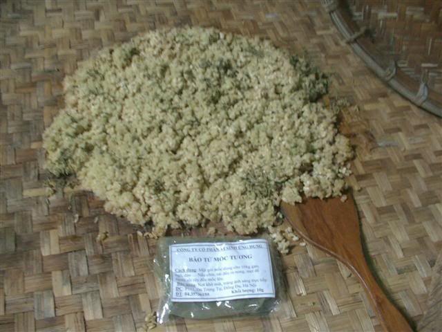 Hộp đựng tương miso màu nâu đặc trưng, đặt cạnh hạt đậu nành và một ít gạo, minh họa nguyên liệu chính.